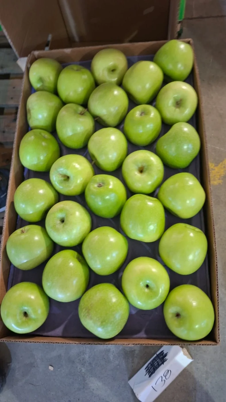 Manzanas verdes presentadas en una caja de cartón